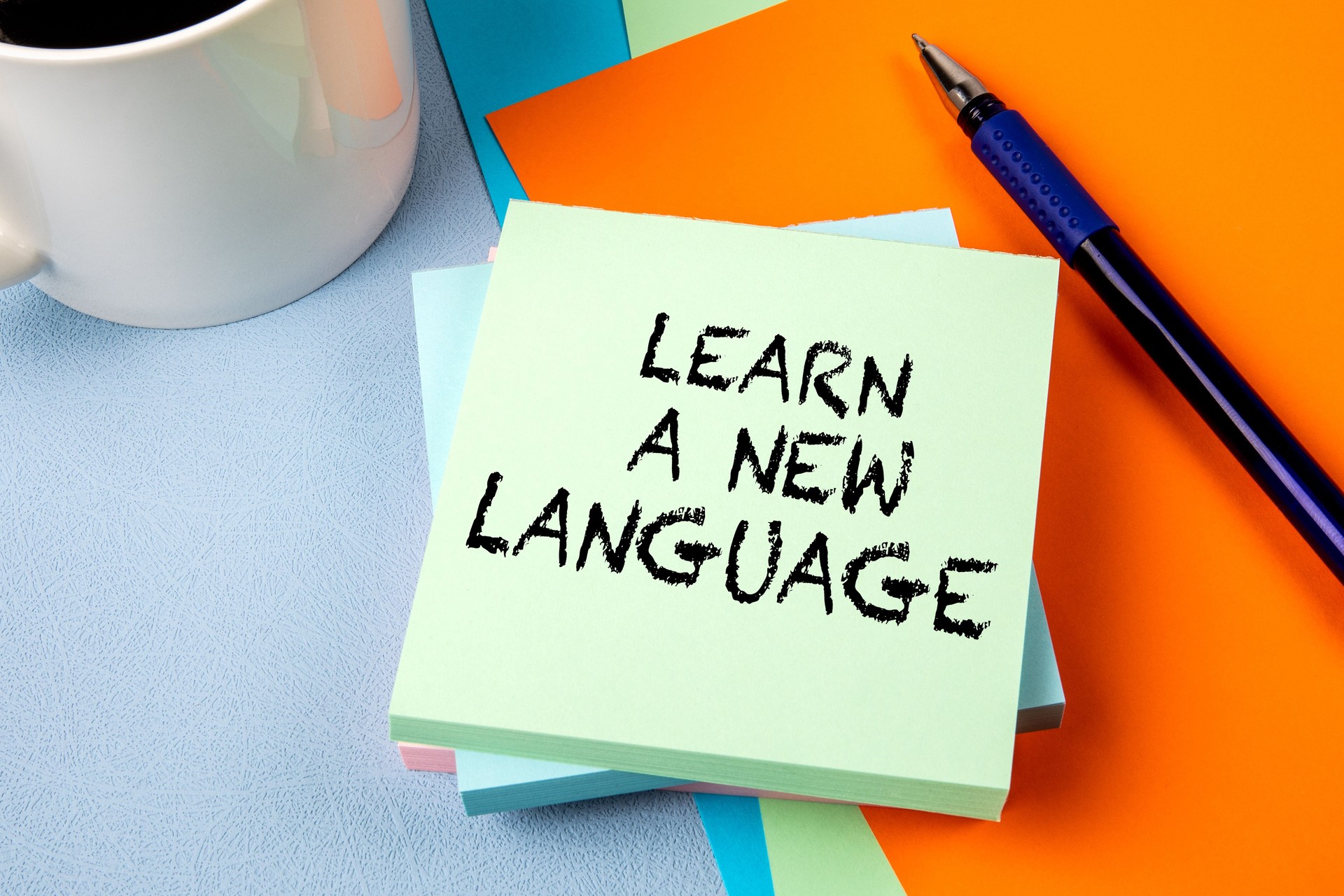 LEARN A NEW LANGUAGE. Notepad with text on office table